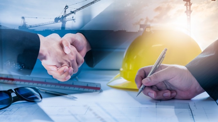 stratta di mano e firma documento vicino a casco cantiere